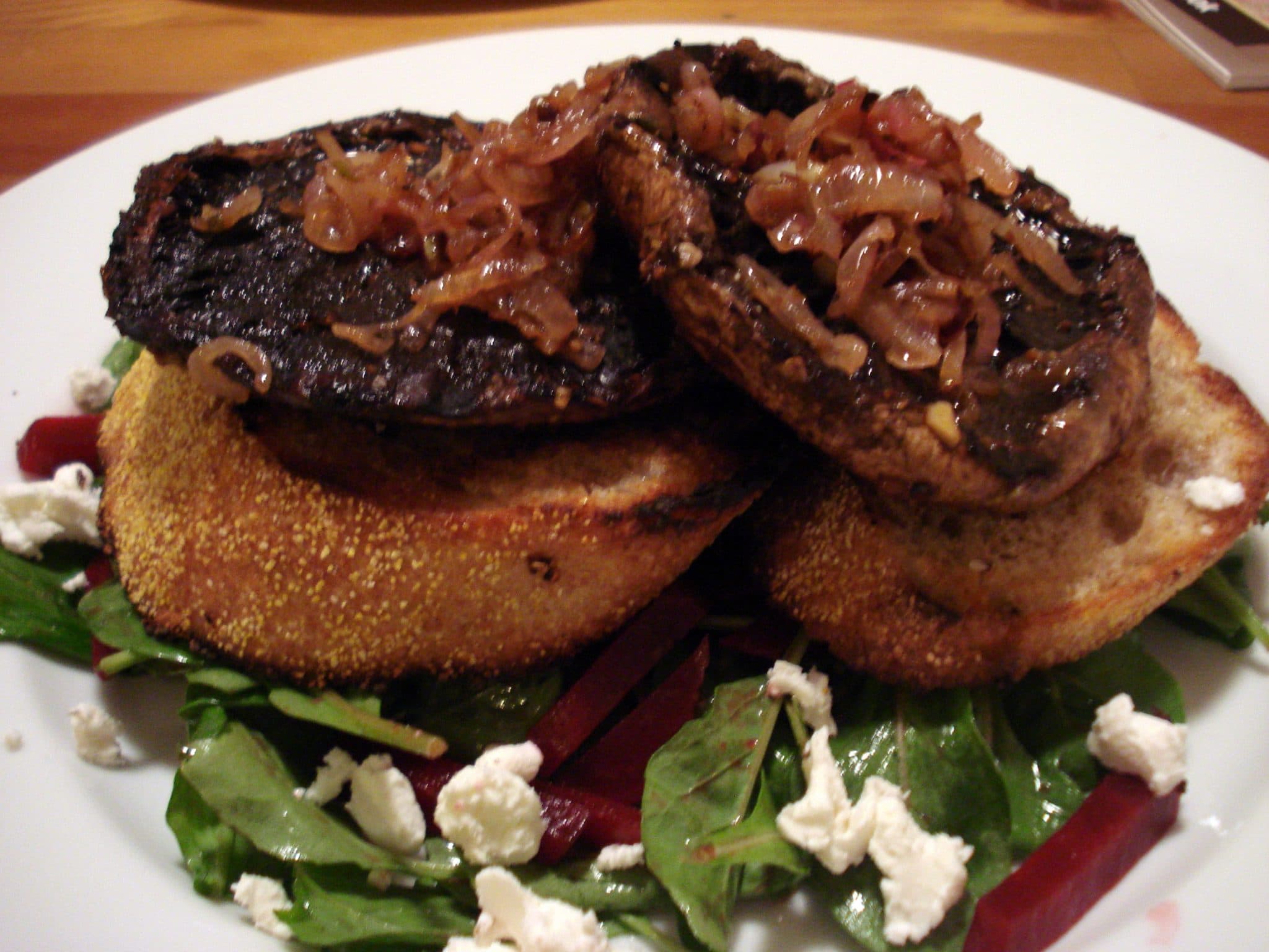 Open faced Grilled Portobello Bistro Burgers on top of green salad