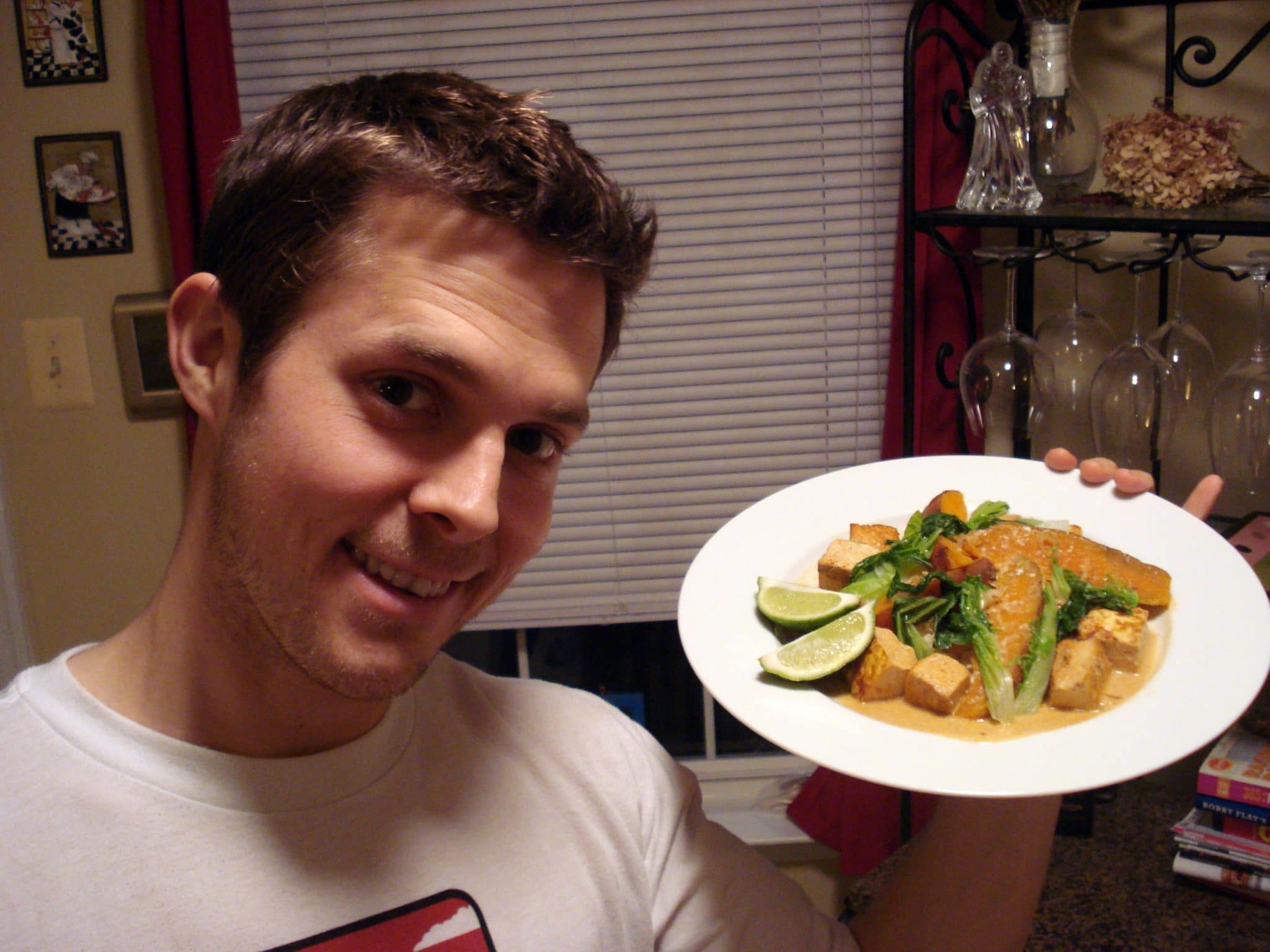 Matt holding plate of Sweet Potato Curry with Tofu, Bok Choy, and Caramelized Shallots with Lime