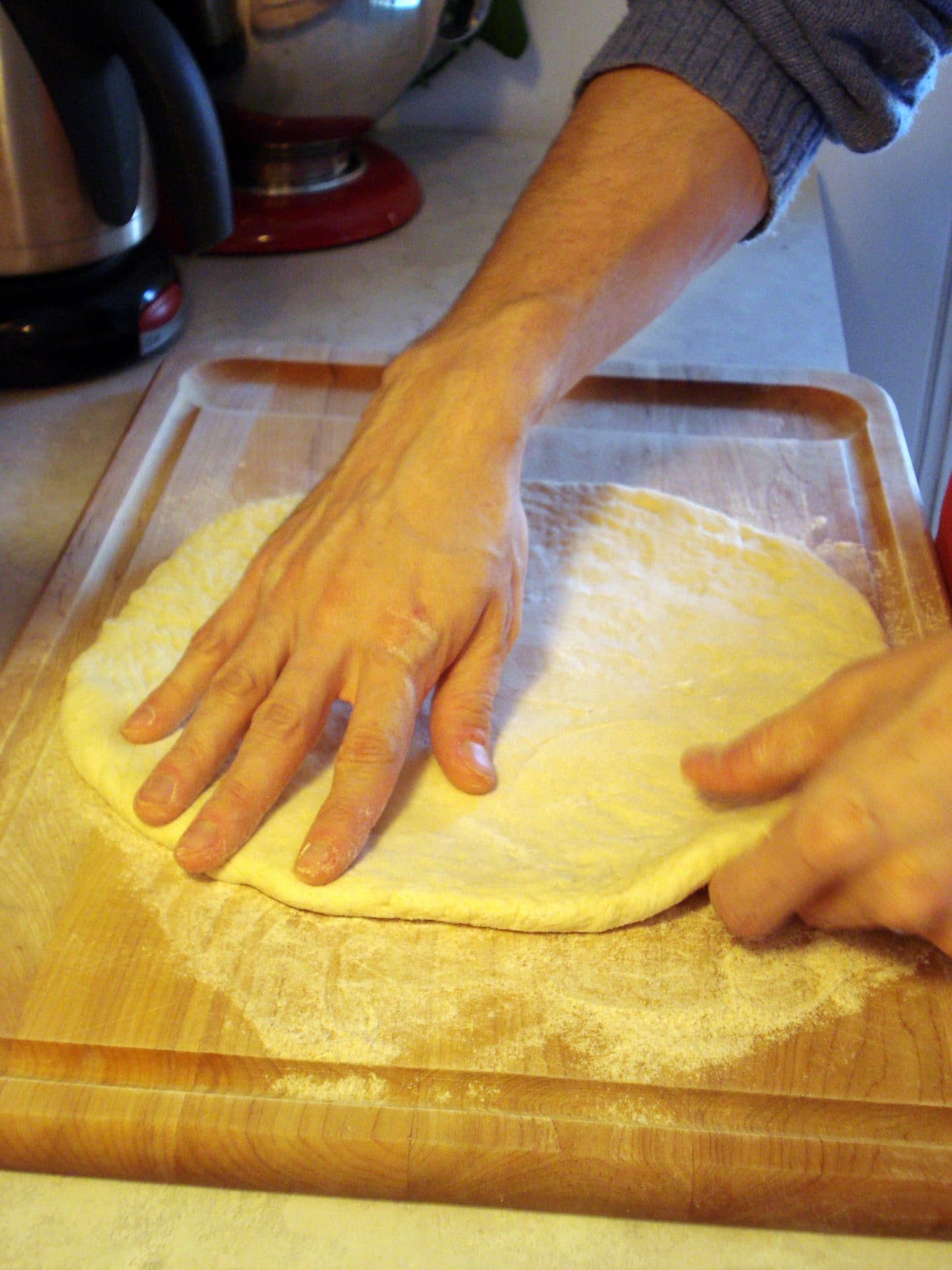 Man kneading pizza dough on kitchen counter