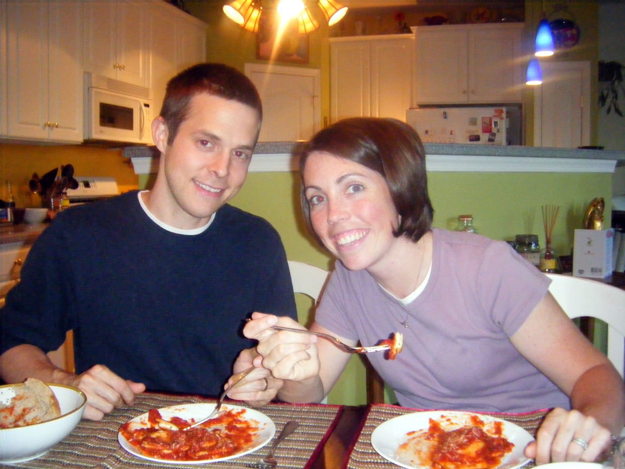 Man and woman eating dinner at table, smiling for camera