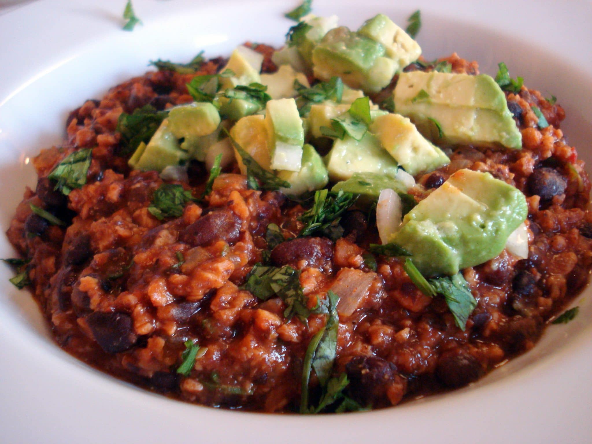 Bowl of Smoky Chipotle Chili with Black Beans and TVP topped with fresh avocado