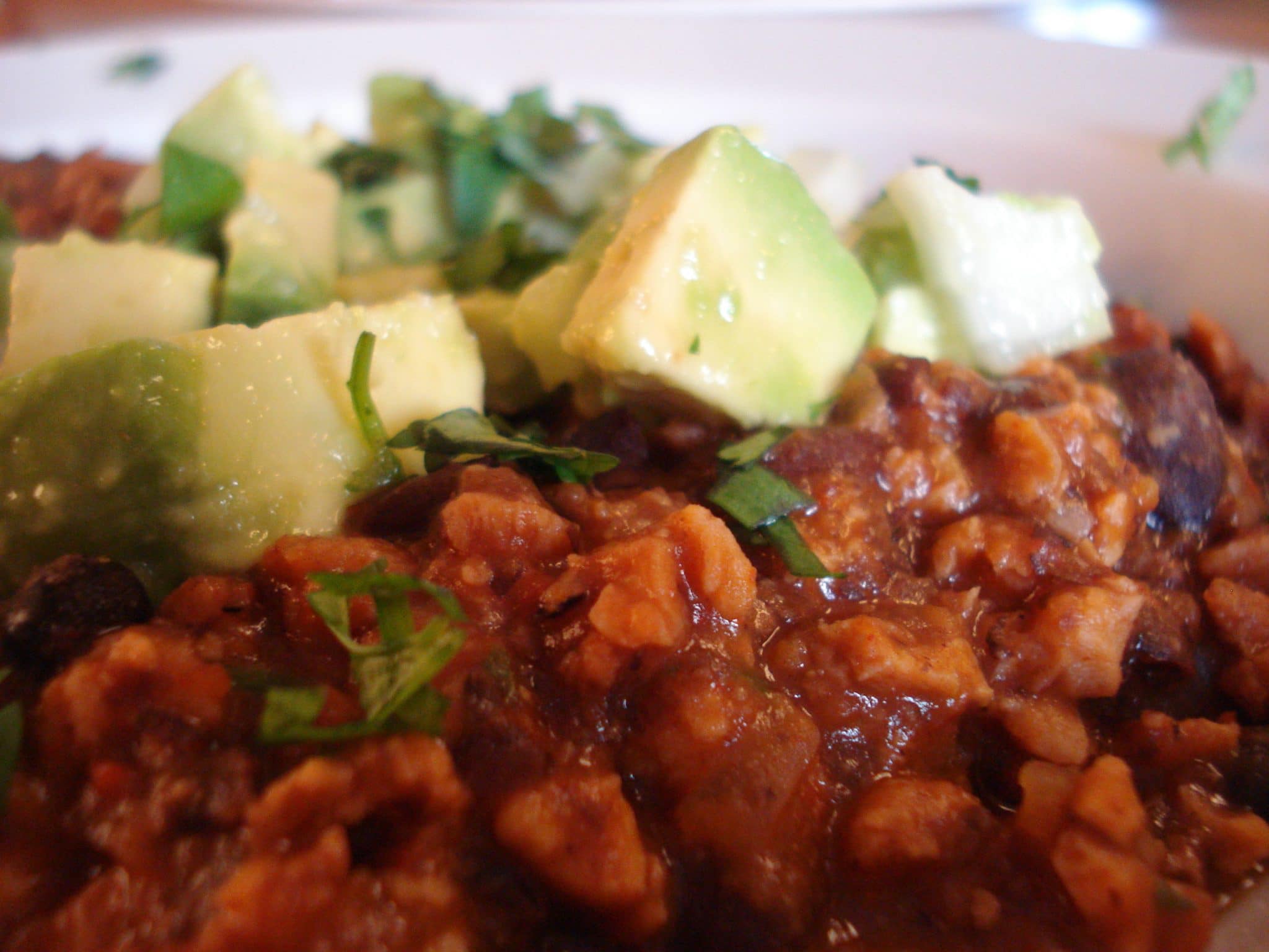 Close up of Smoky Chipotle Chili with Black Beans and TVP topped with avocado