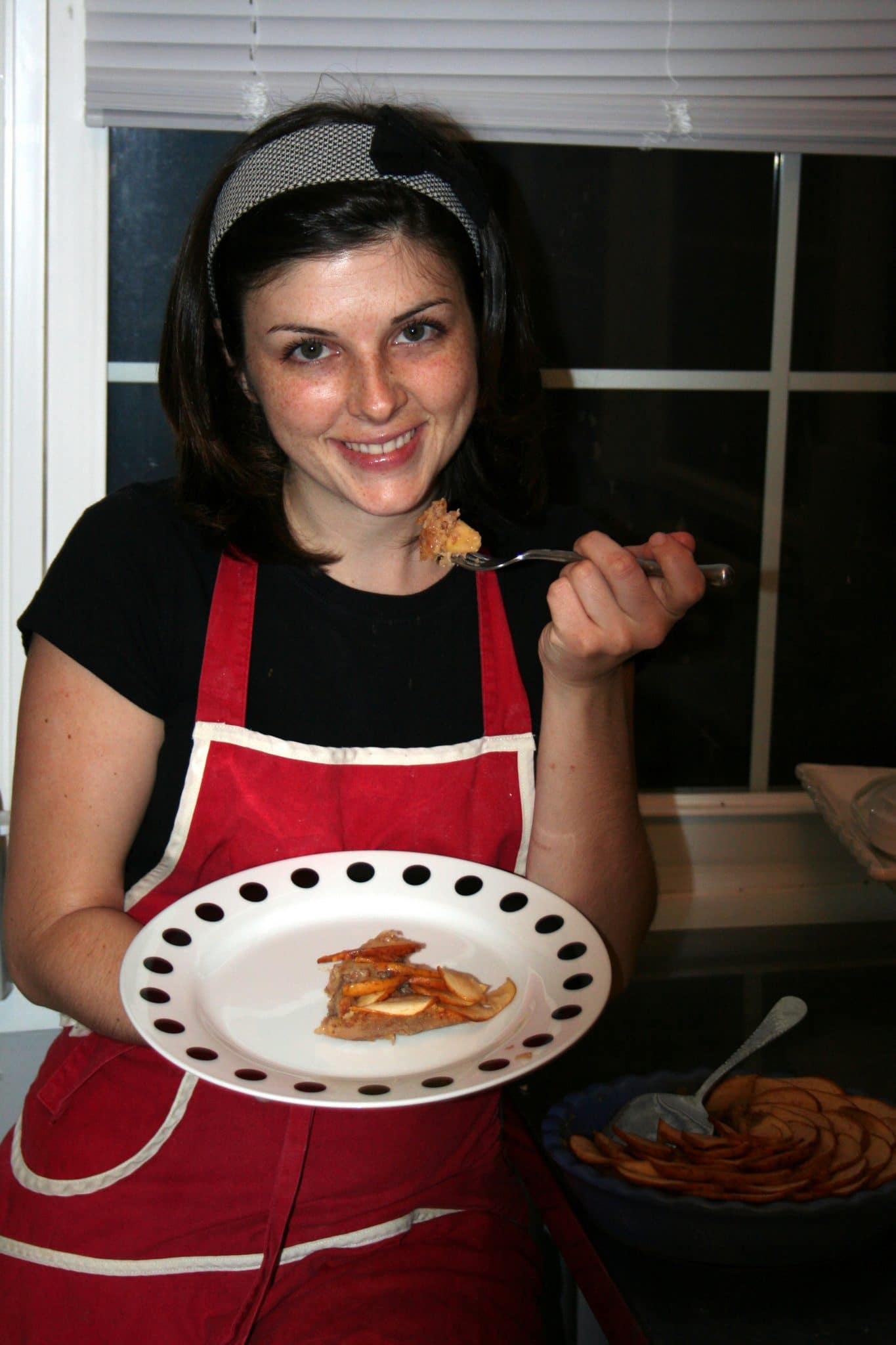 Woman eating apple-pinot tart in plate with fork