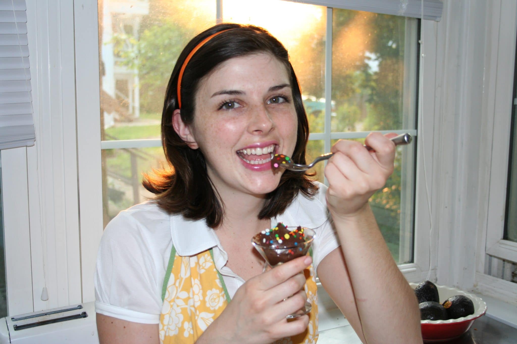 Woman eating Avocado Peanut Butter Mousse in glass with sprinkles