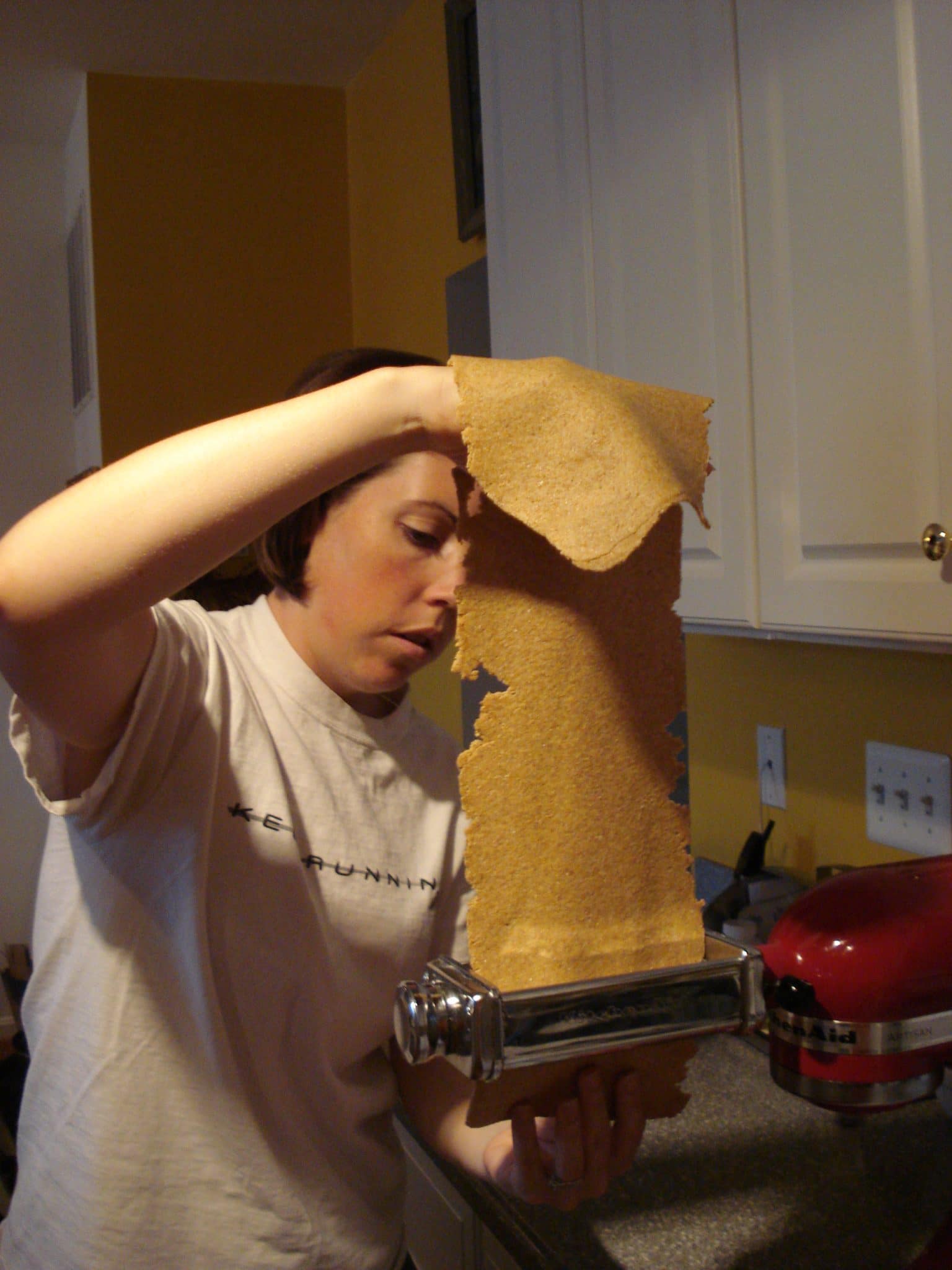 Woman running pasta dough through pasta cutter, Kitchenaid attachment