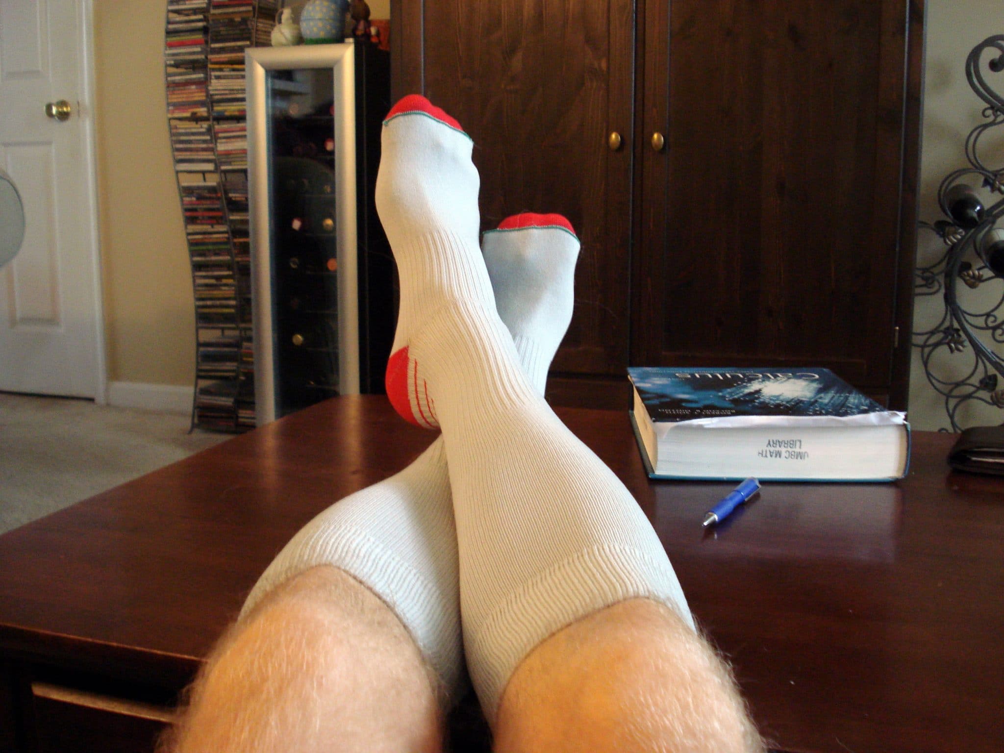 Legs propped up on coffee table wearing white compression socks with red toes