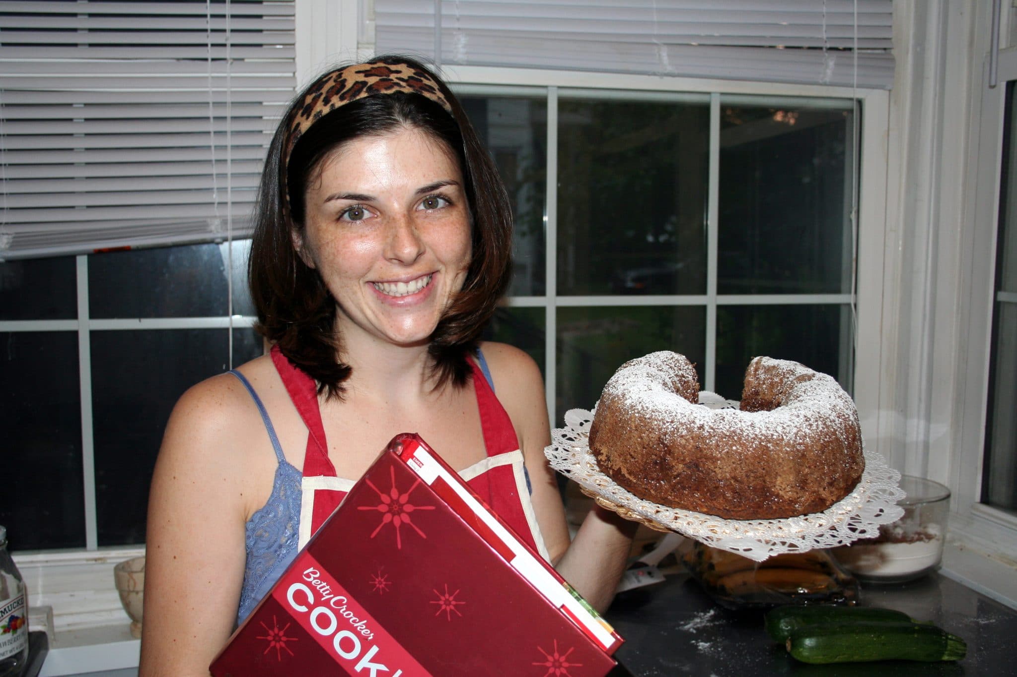 Woman holding Lemon Poppy Zucchini Bread and cookbook