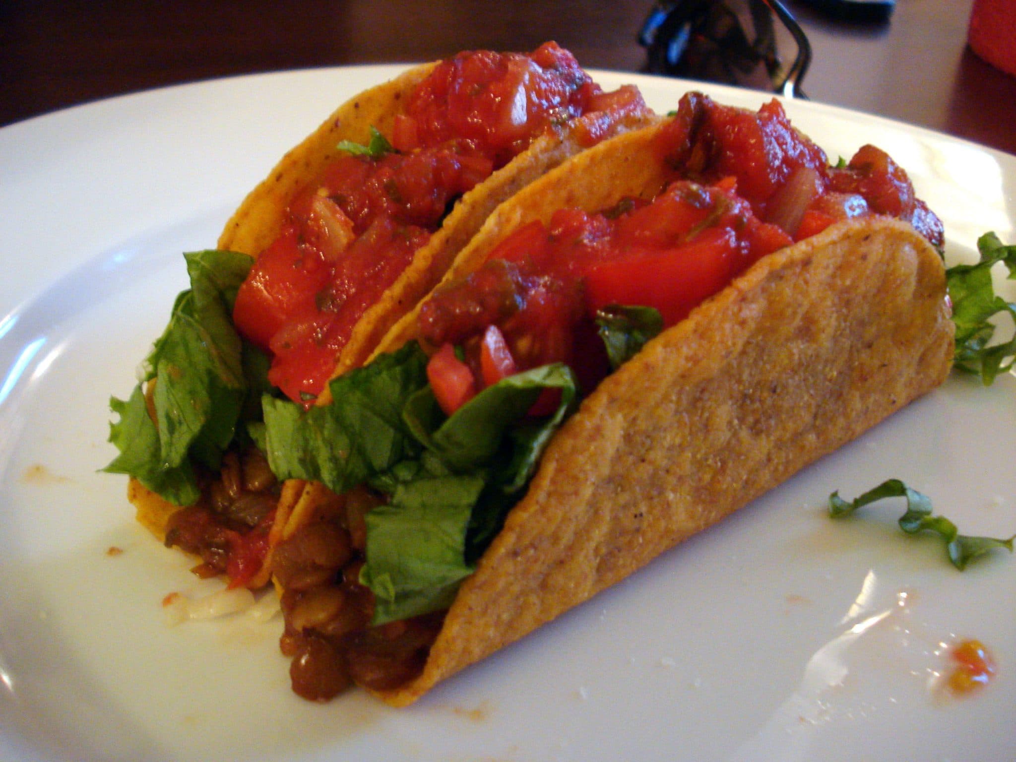 2 lentil tacos with shredded lettuce and fresh tomatoes, topped with salsa