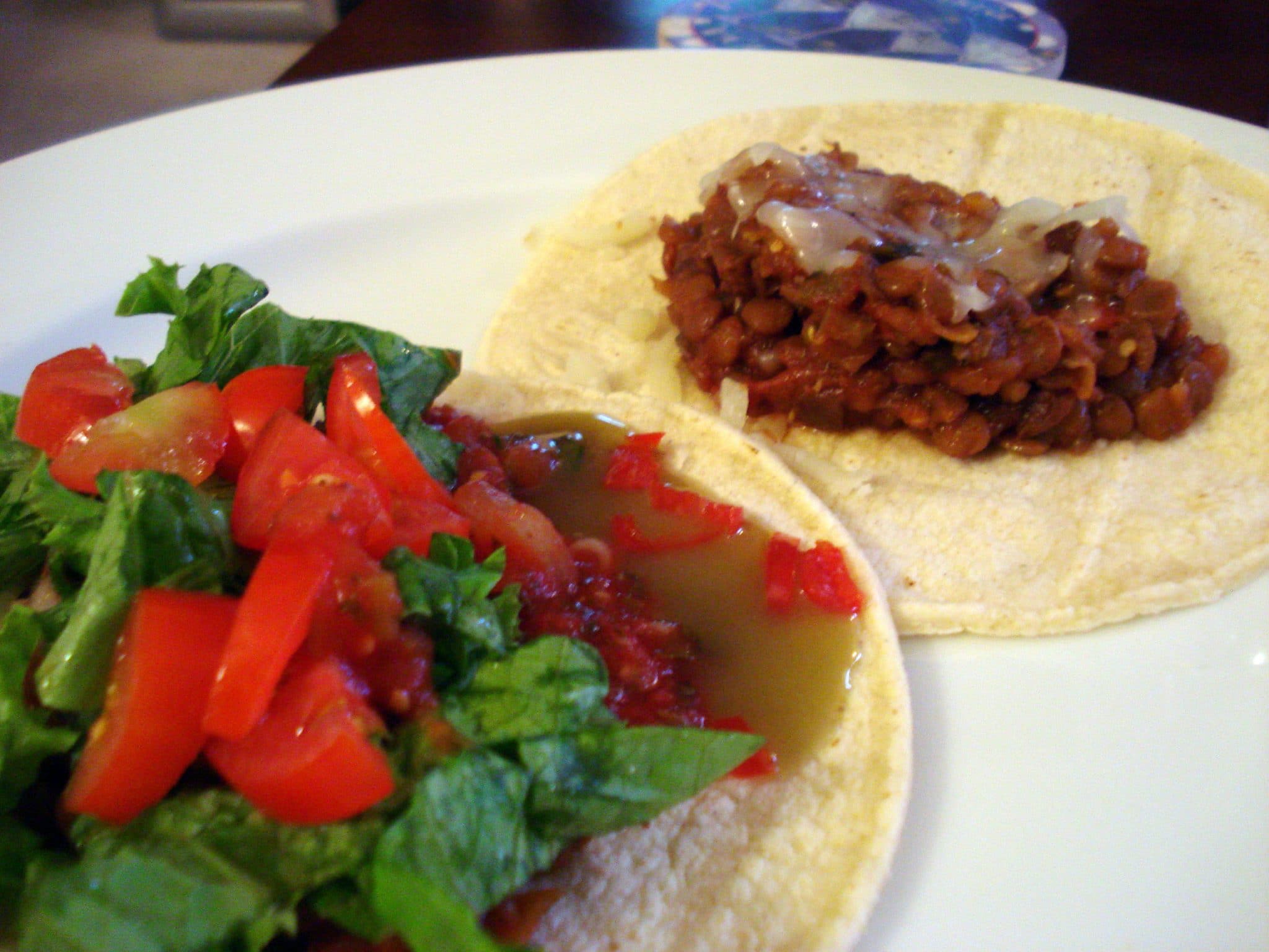 Plate of lentil tacos and taco toppings on the side