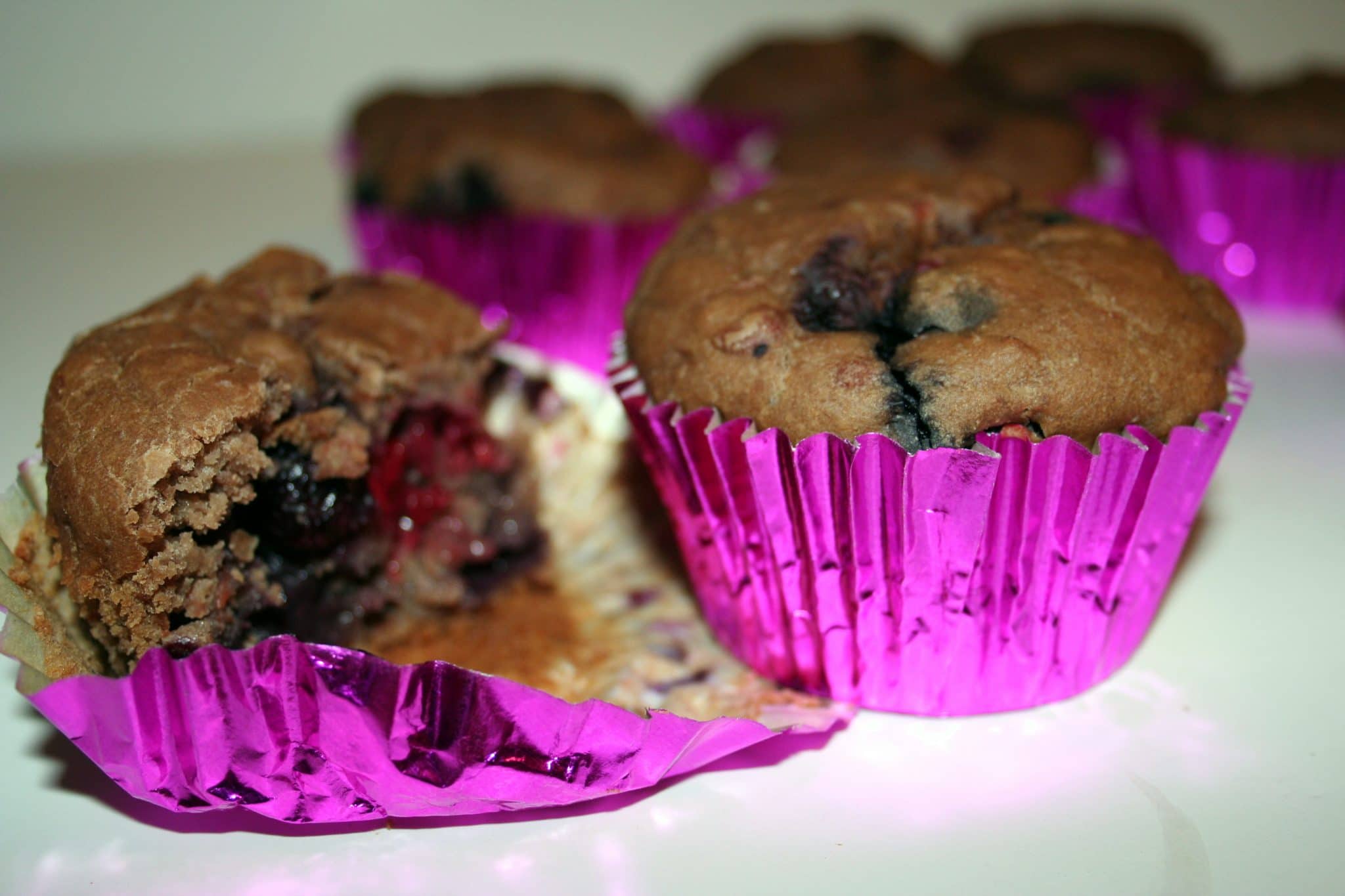 Close up of 2 Vegan Pink Bean & Berry Muffins, one cut in half
