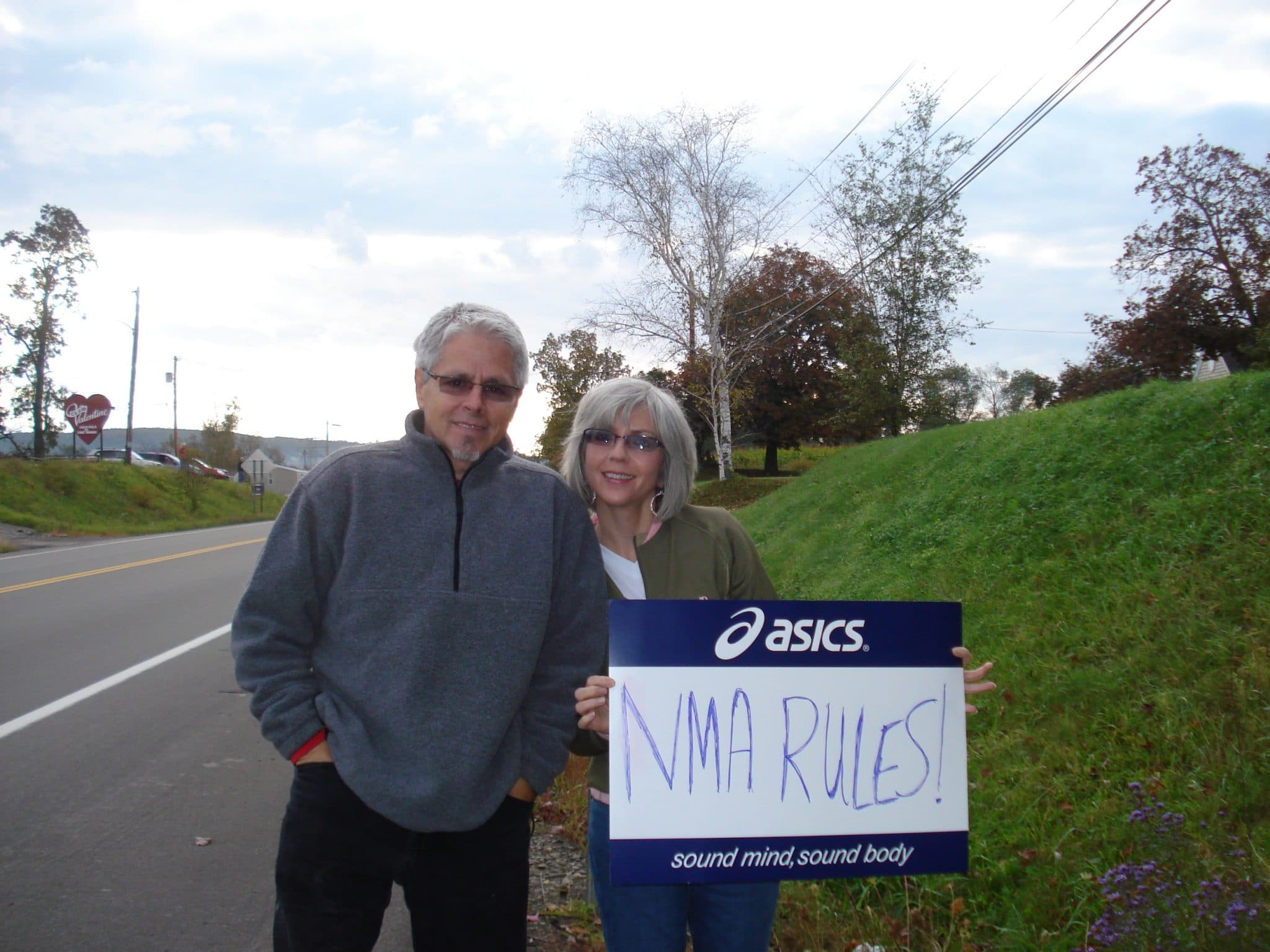 Matt's parents with "NMA Rules" sign cheering runners