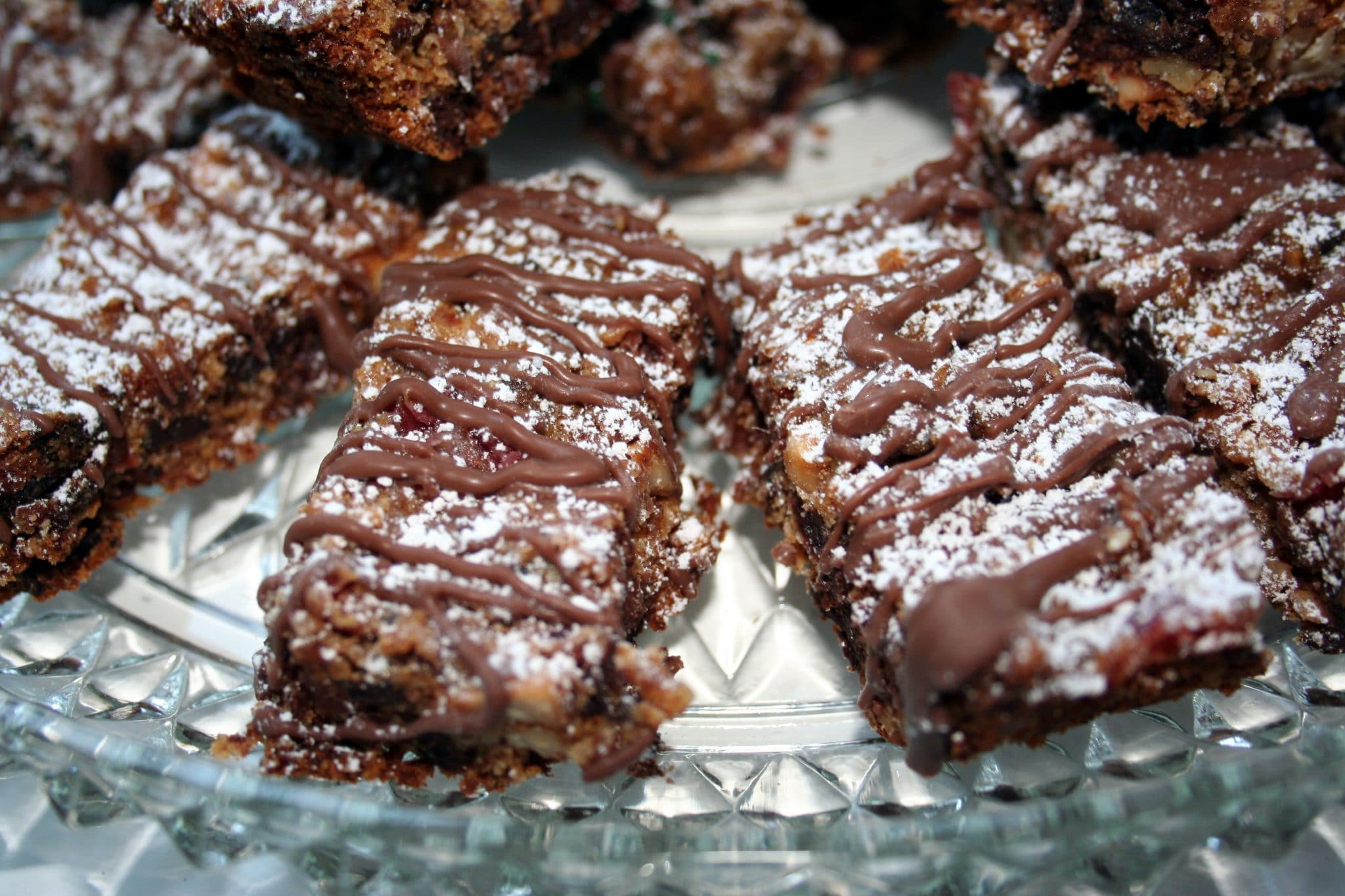 Plate of Vegan Jubilee Bars with chocolate drizzle and powdered sugar
