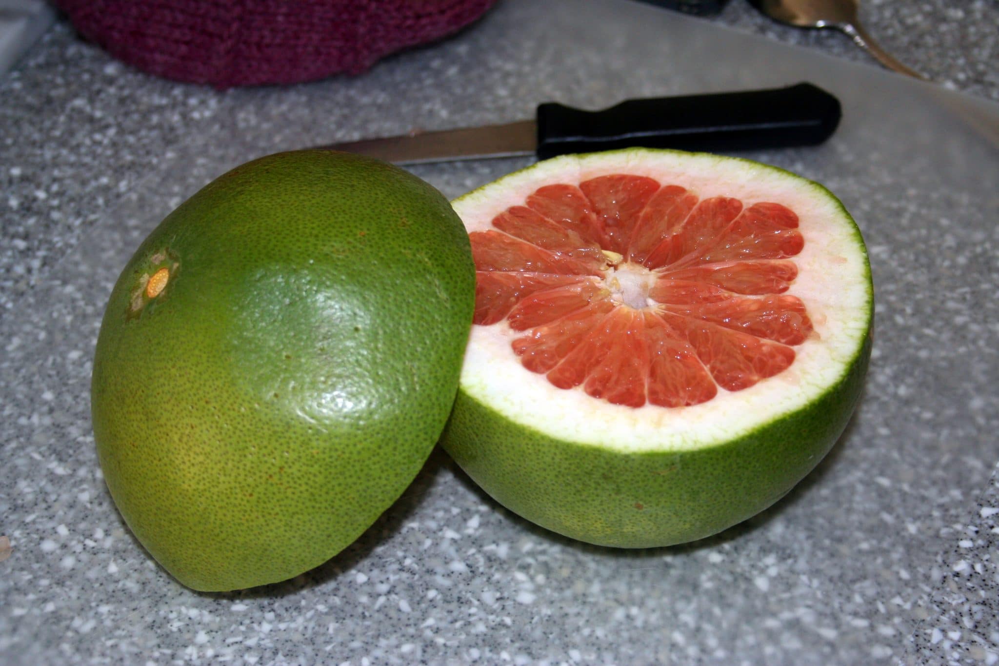 Pomelo sliced in half to show interior, looks like grapefruit.