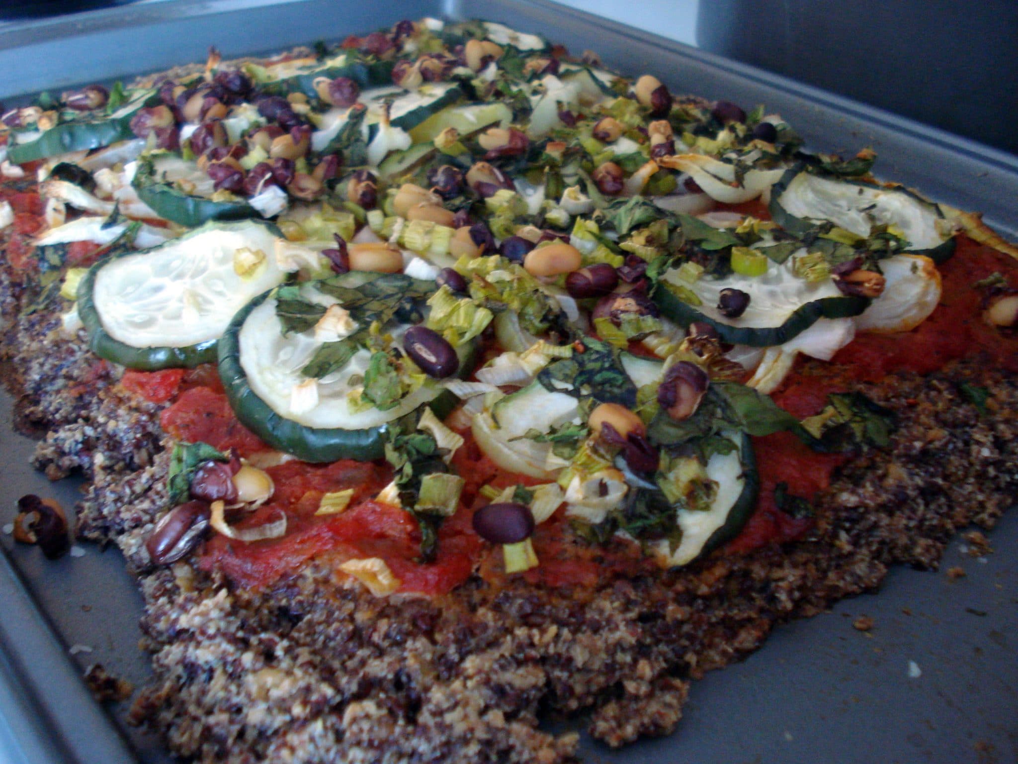 Adzuki Bean Quinoa Sesame Pizza topped with marinara sauce, zucchini and beans