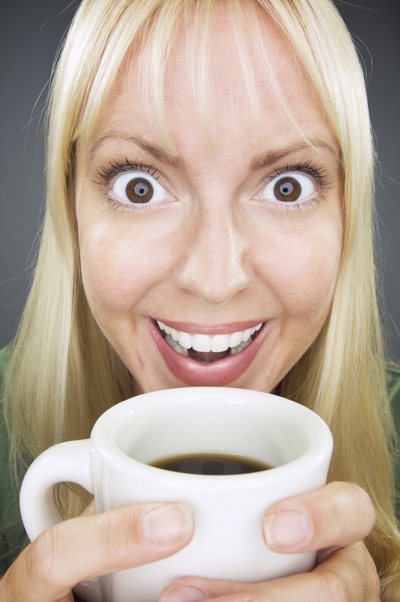 Blonde caffeinated woman holding cup of coffee with eyes wide open