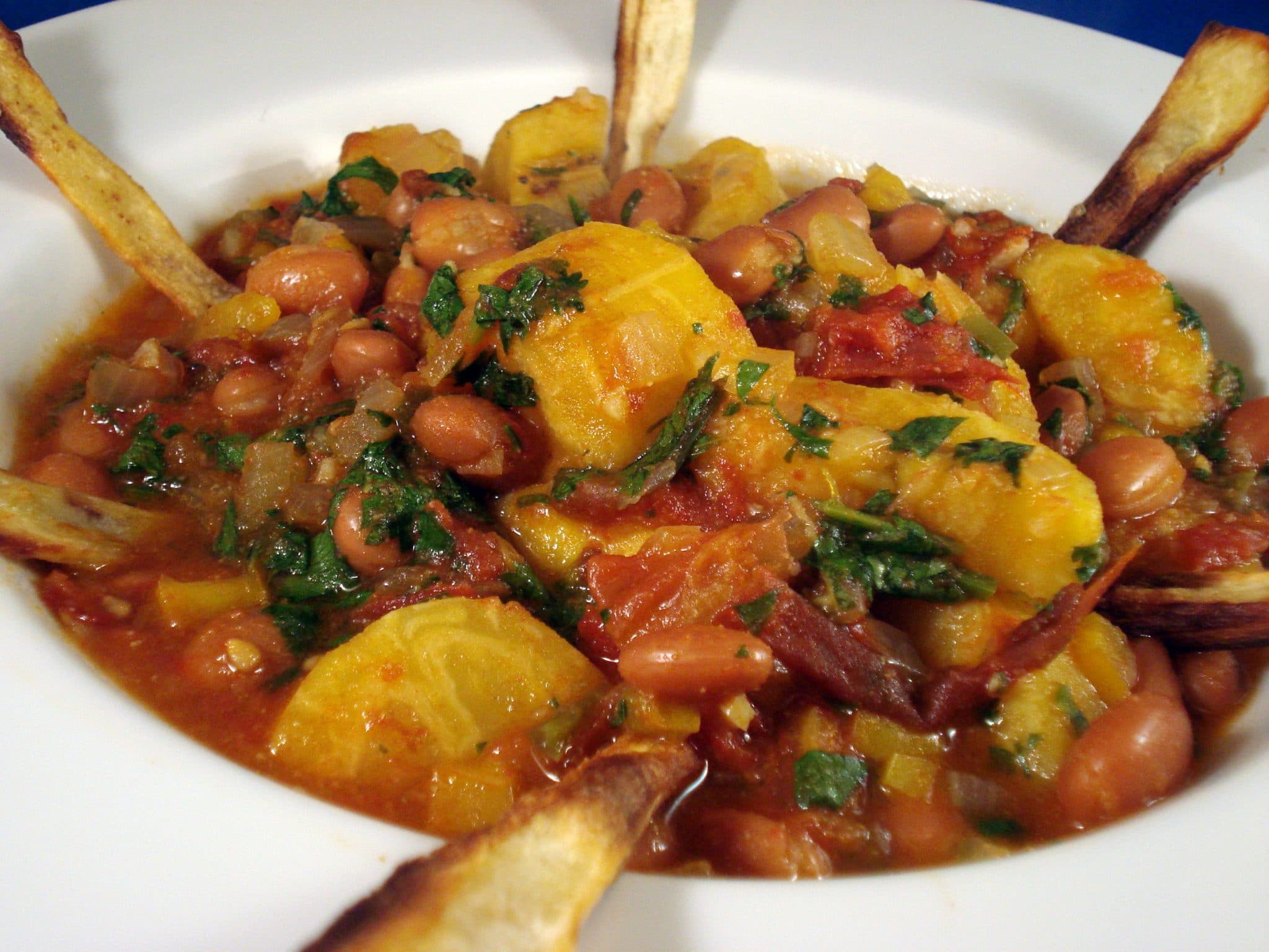 Bowl of vegan Plantain and Pinto Stew with Parsnip Chips