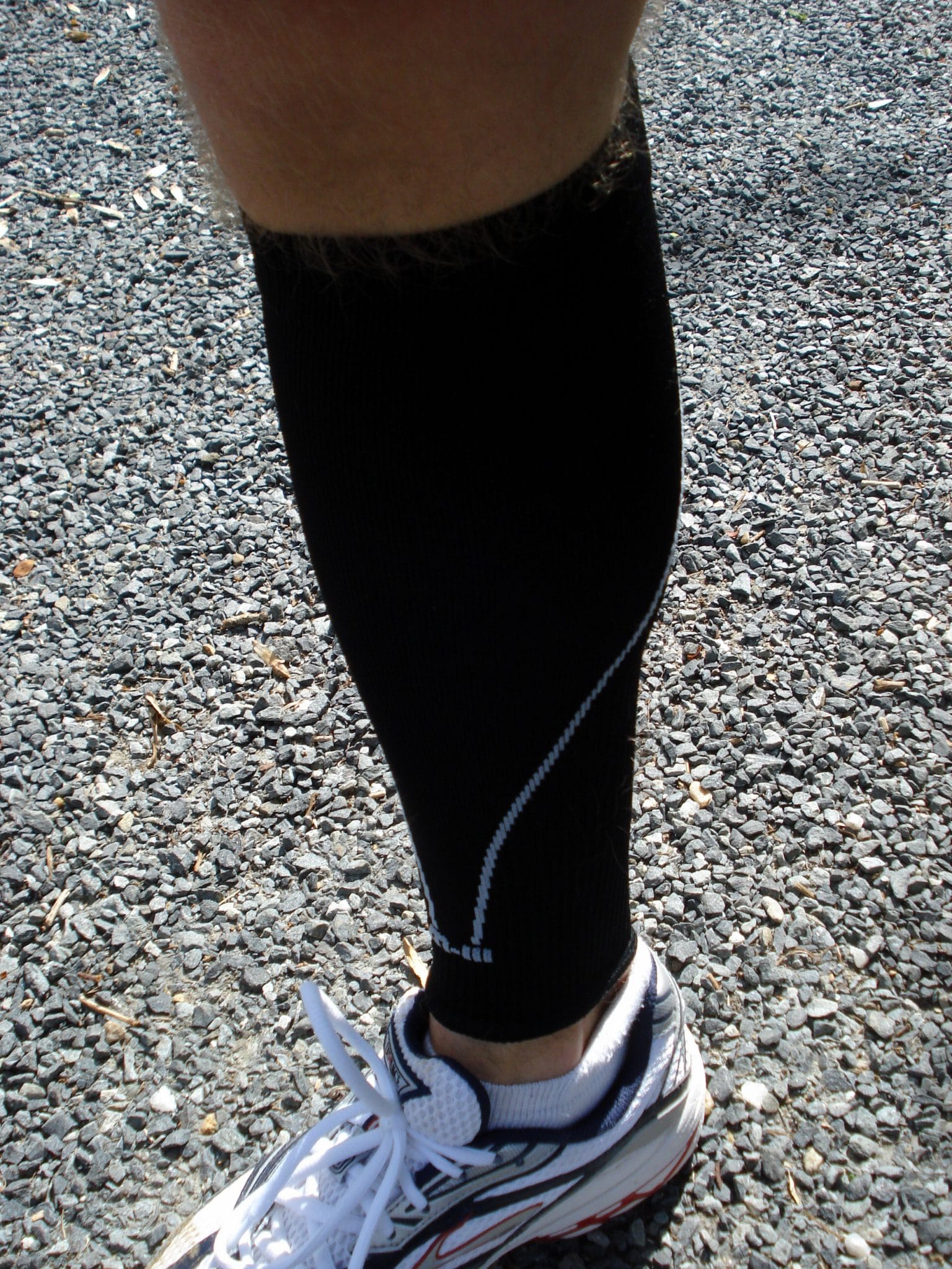 Image of leg wearing black compression sock and running sneaker