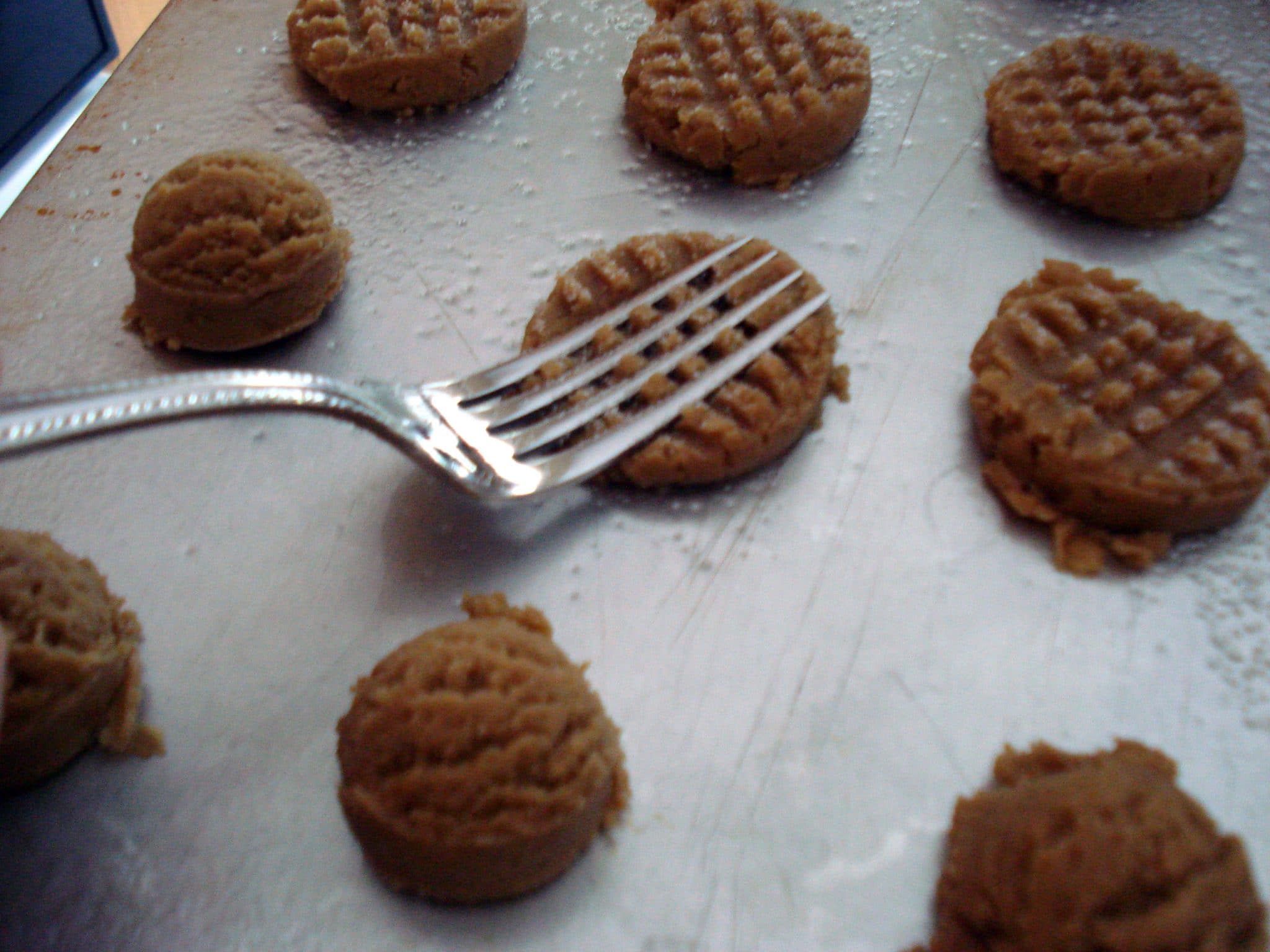 Raw peanut butter cookies being pressed by a fork