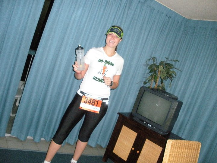 Woman in white throwback carrot shirt in living room with race bib on