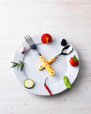 Clock with vegetables used to create clock, fork and spoon as hour and minute hand