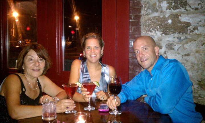 Tom enjoying a meal out at a restaurant with family drinking wine