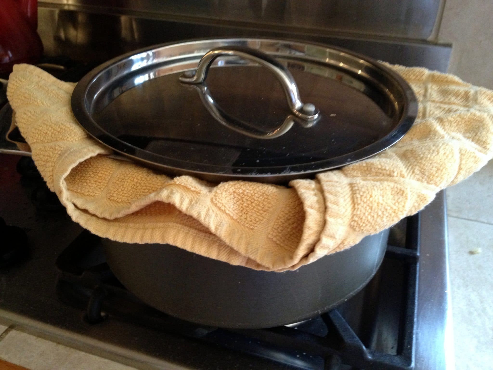 Cooked rice back in large soup pot with towel over top, and lid on top of towel