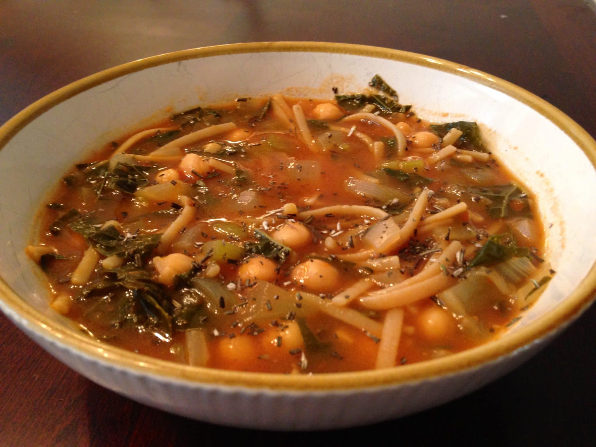 White bowl of hearty chickpea pasta soup