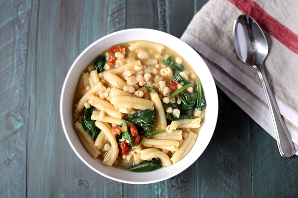 Bowl of Pasta e Fagioli on table with spoon and cloth napkin