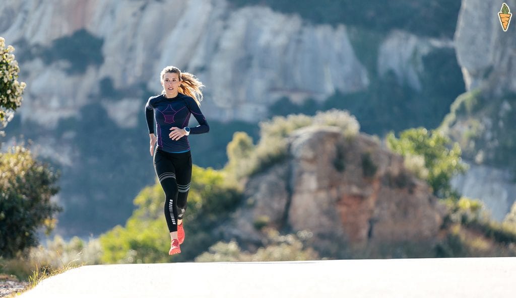 Woman running fast up incline with mountains in the background