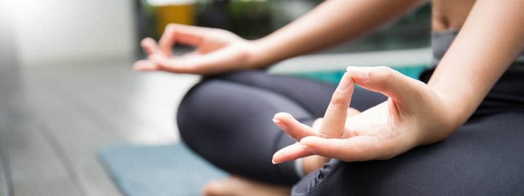 Hands on knees with middle finger touching thumb, in meditation