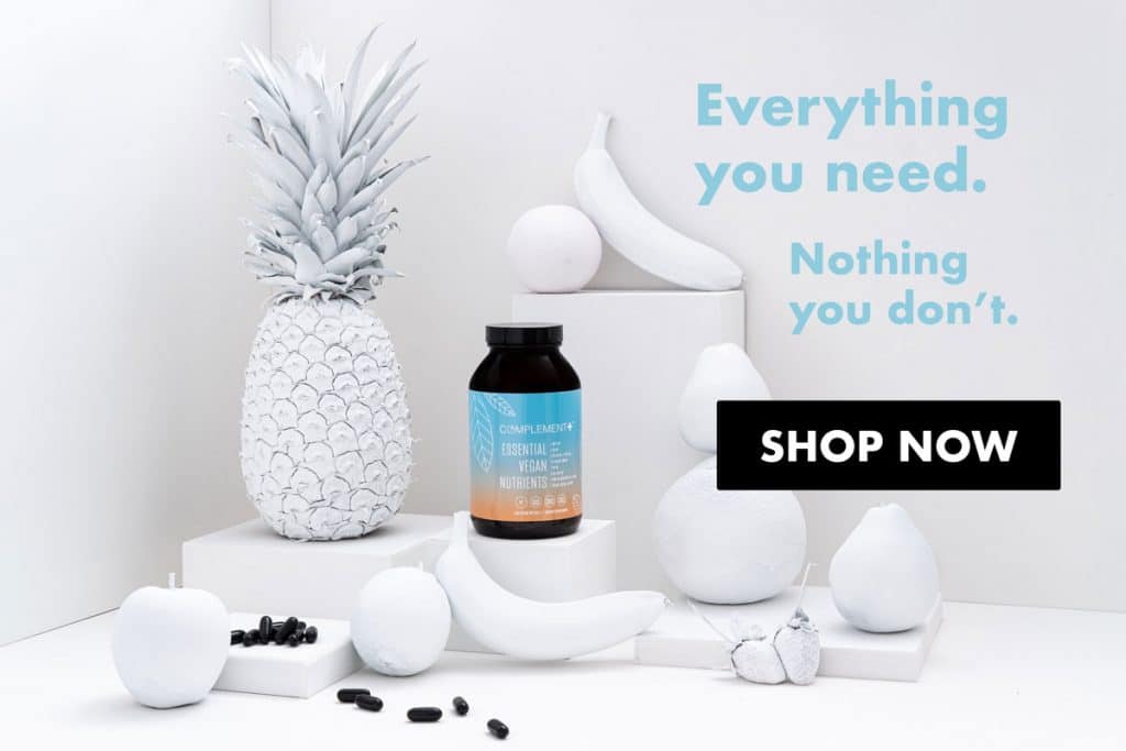 Vegan multivitamin Complement Plus bottle in full color bottle next to white fruits